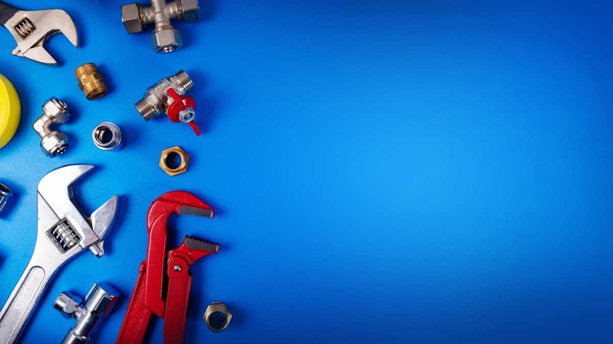 Assorted plumbing tools and fittings on a blue background.