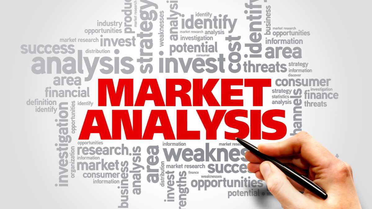 Word cloud related to market analysis with MARKET ANALYSIS in bold red hand holding a pen