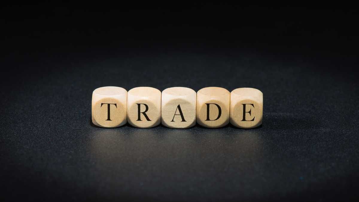 Wooden dice spelling TRADE on a black background