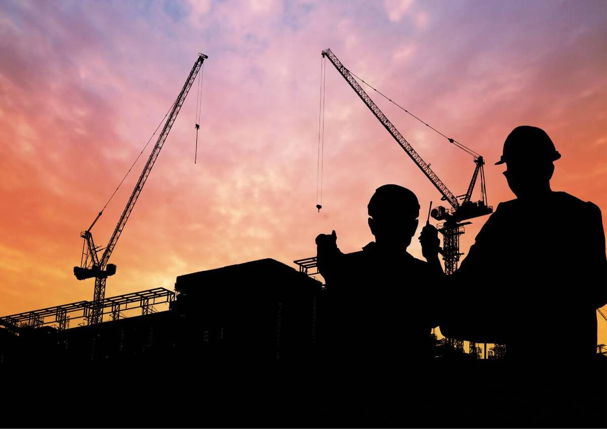 Silhouettes of construction workers at sunset, indicating building or development