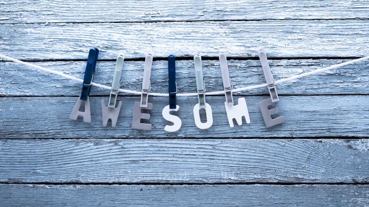 The word AWESOME is spelled out and hung on clips on a wooden background