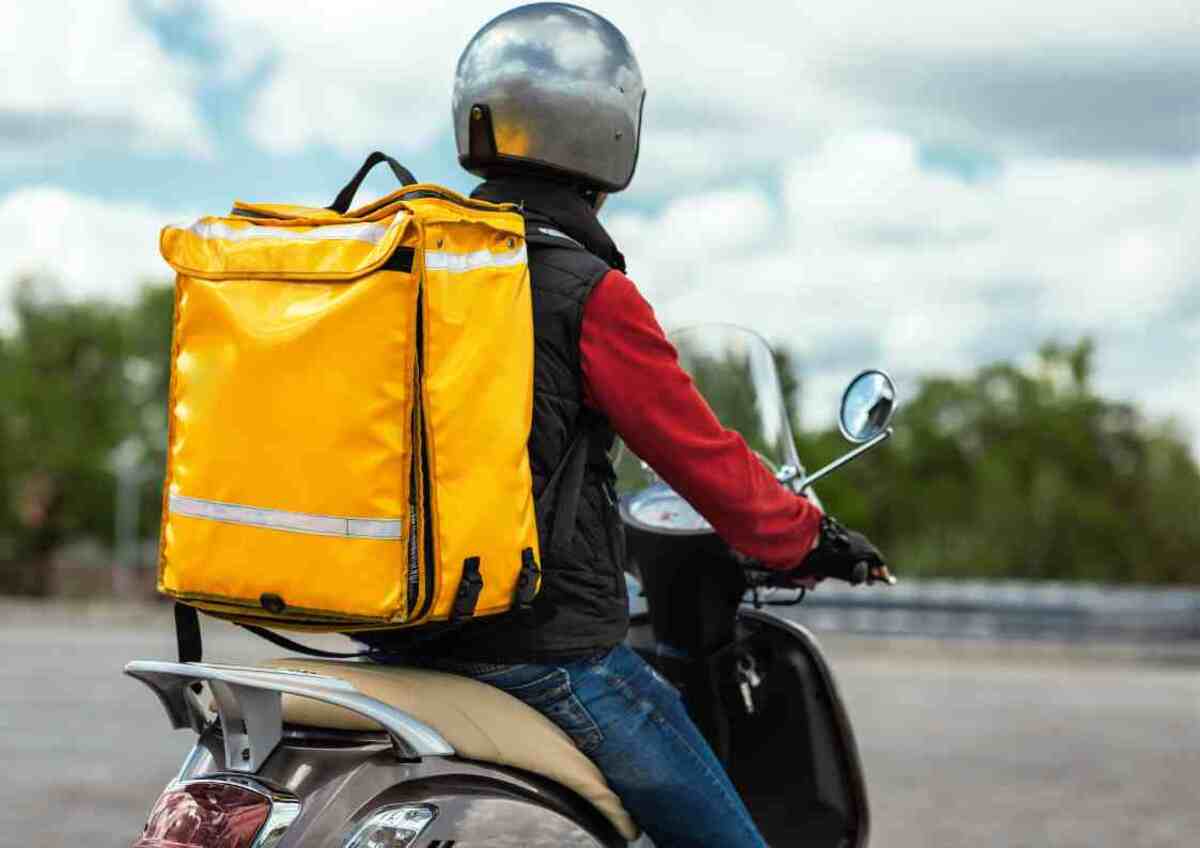 Food Delivery Courier With Yellow Backpack Riding Motorbike Outdoors Rear View