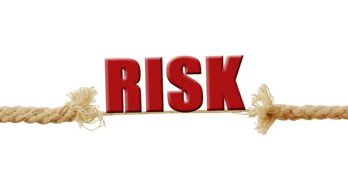 The image shows the word RISK in red letters balanced on a tightrope made of a fraying rope