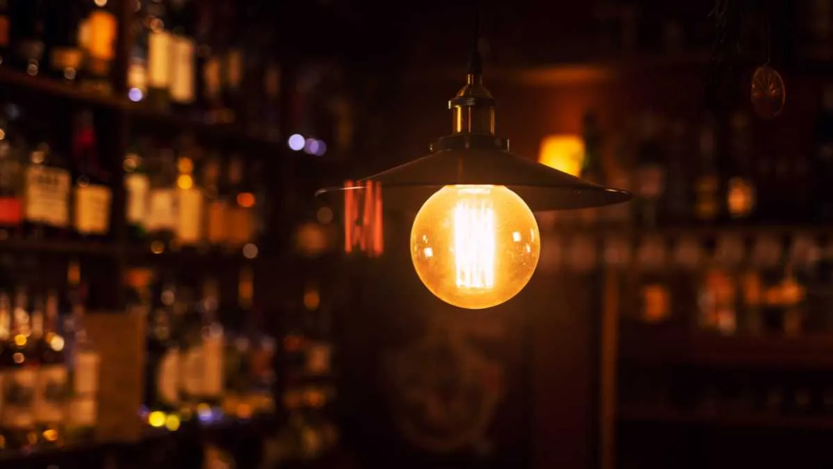 A warm glowing light bulb illuminates a dimly lit bar setting