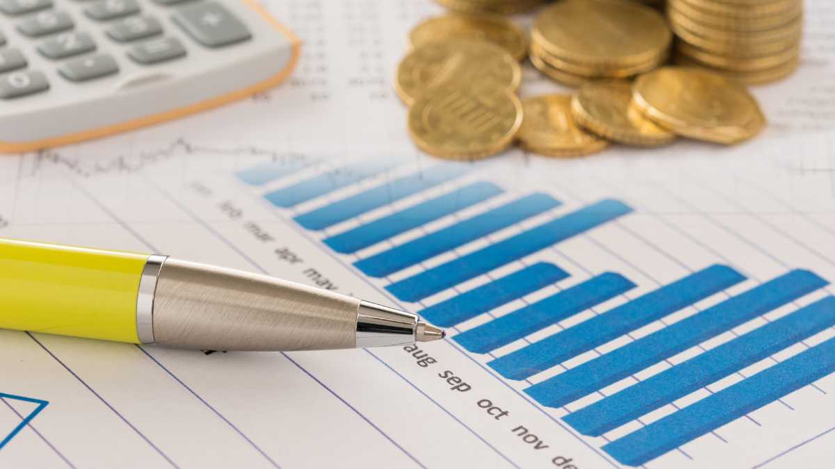 Financial chart with blue bars, calculator, coins, and a pen.