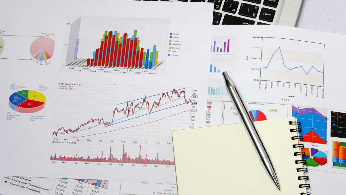 Various financial charts on paper with a pen and notebook on a desk