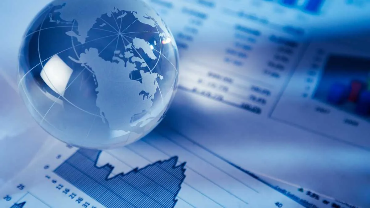 A glass globe on financial papers, suggesting global business analysis