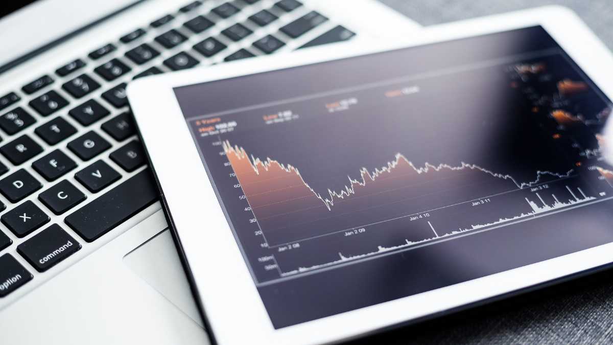 Tablet displaying stock market chart next to a laptop.