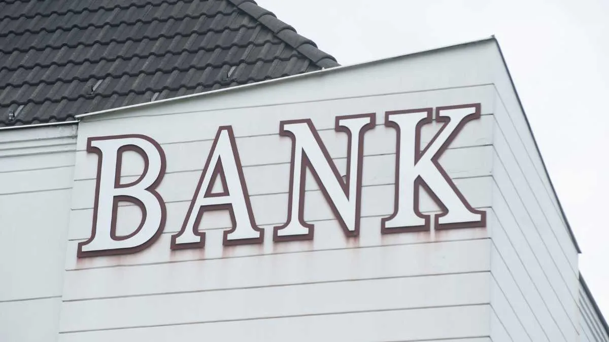 Signage of a bank on the exterior of a building with a clear sky.