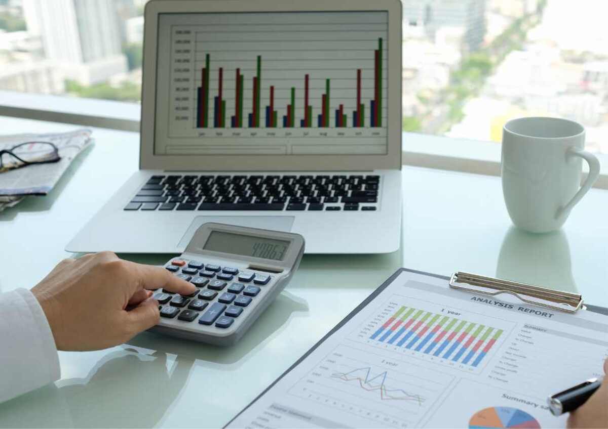 Laptop with a financial growth chart, calculator, and coffee mug.