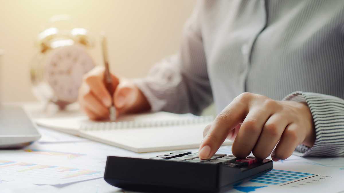 A person is calculating finances with a calculator and writing notes