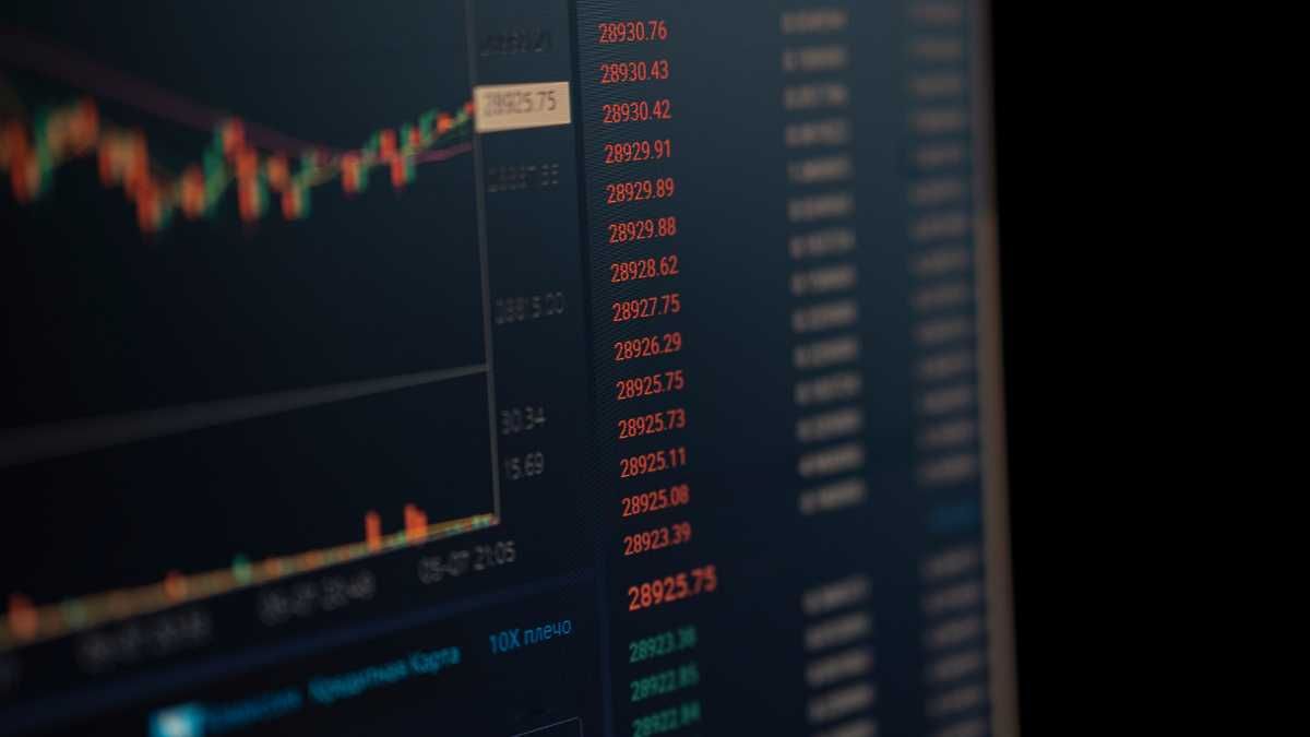 A stock market monitor displaying various stock prices in red and green, indicating market fluctuations