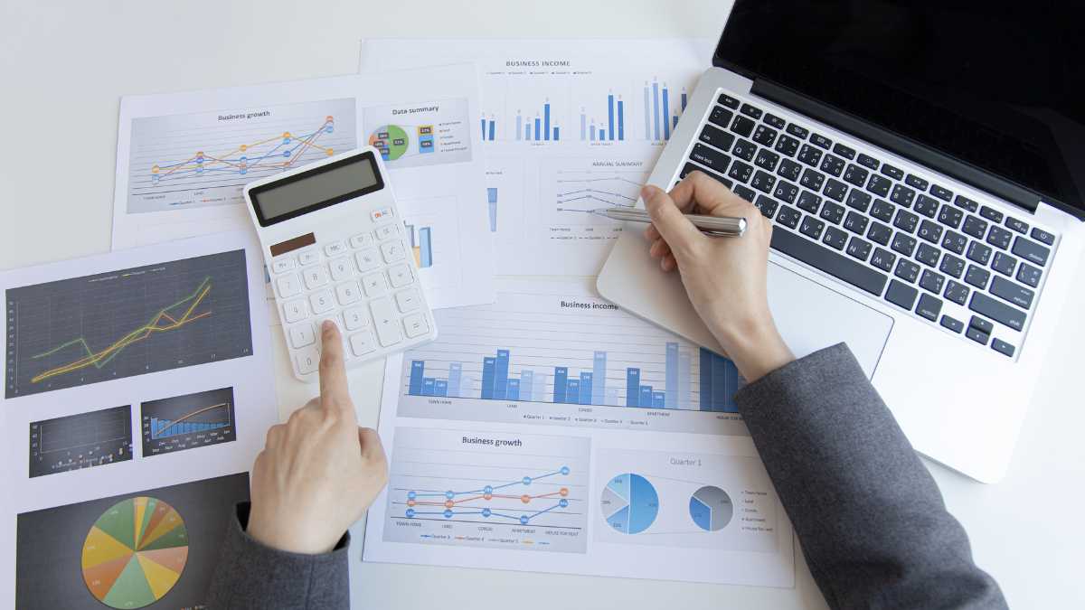 Overhead view of hands with a calculator and financial charts on a desk