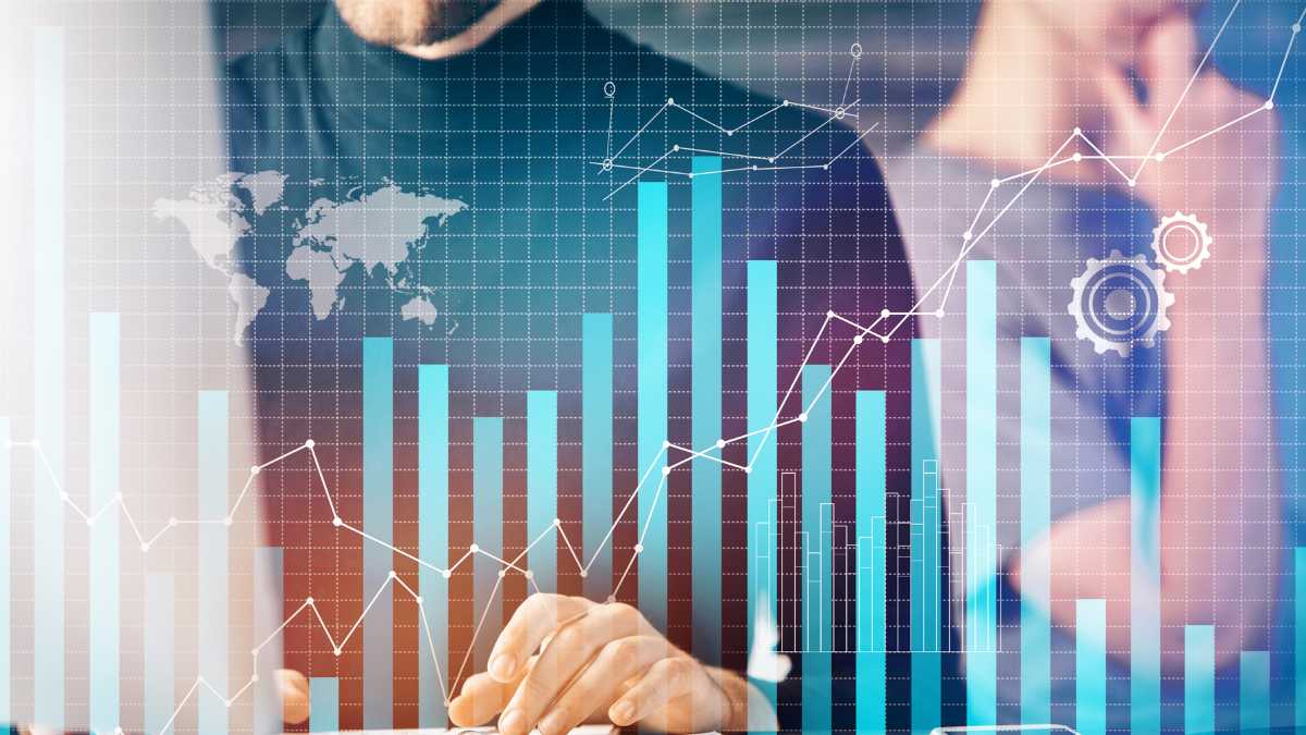 A business person analyzes growth charts and data with a world map in the background