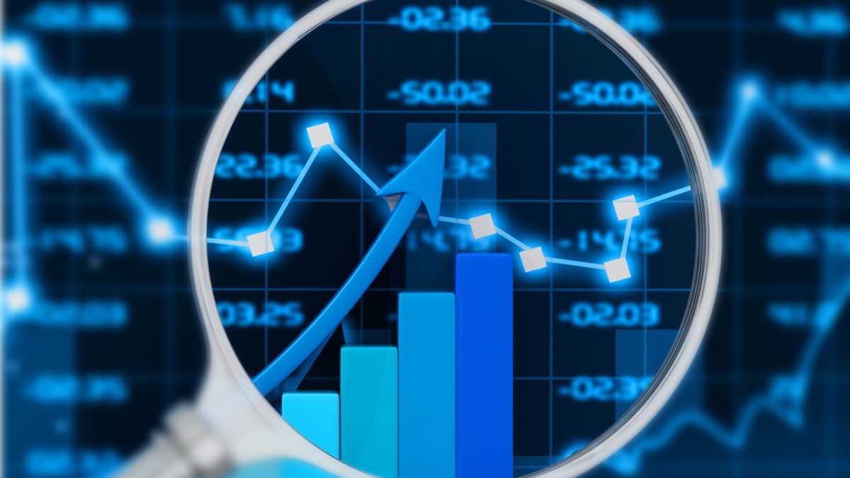 A magnifying glass enhances a graph and blue bars depicting an upward trend in the market