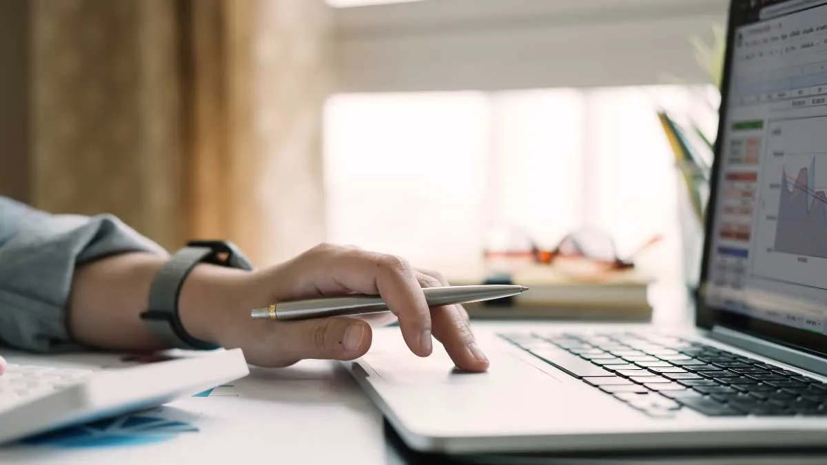 Person using a pen on a laptop trackpad, checking on charting platforms