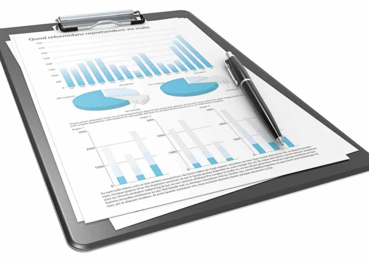 Clipboard and financial report with bar graphs, pie charts, and a pen