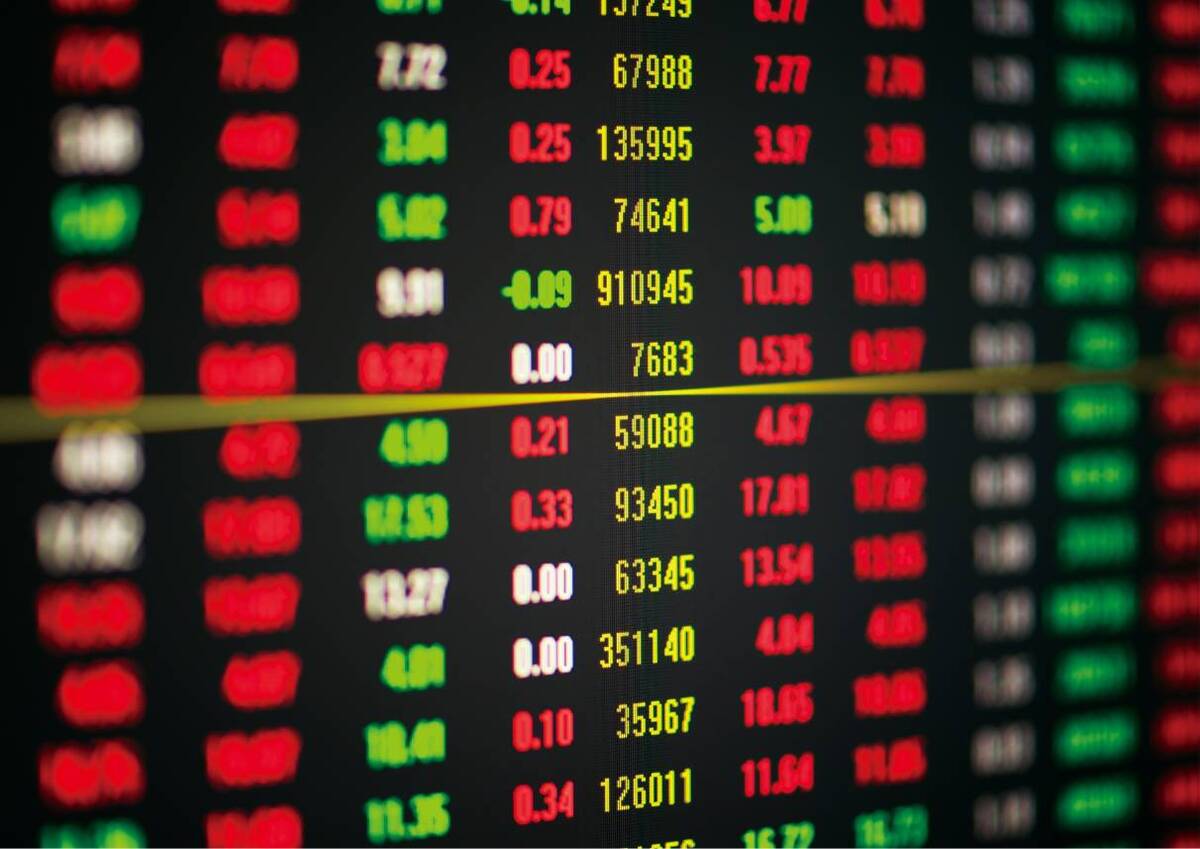 Close up of a blurred stock exchange board showing fluctuating stock numbers in red and green