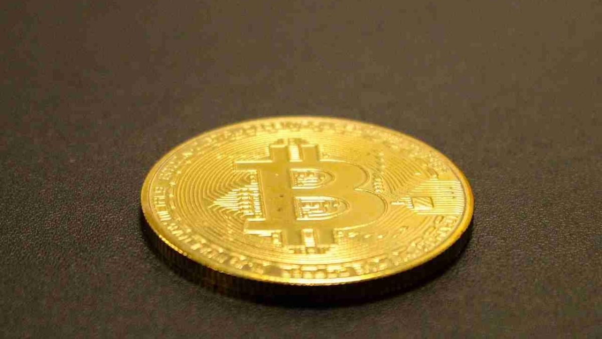 A Bitcoin coated in gold, placed on a flat surface