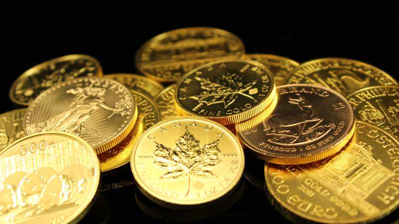 A collection of various gold coins displayed against a black background