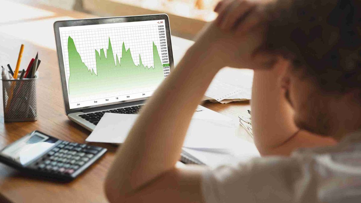 A frustrated man gazes at the laptop on the table expressing discontent