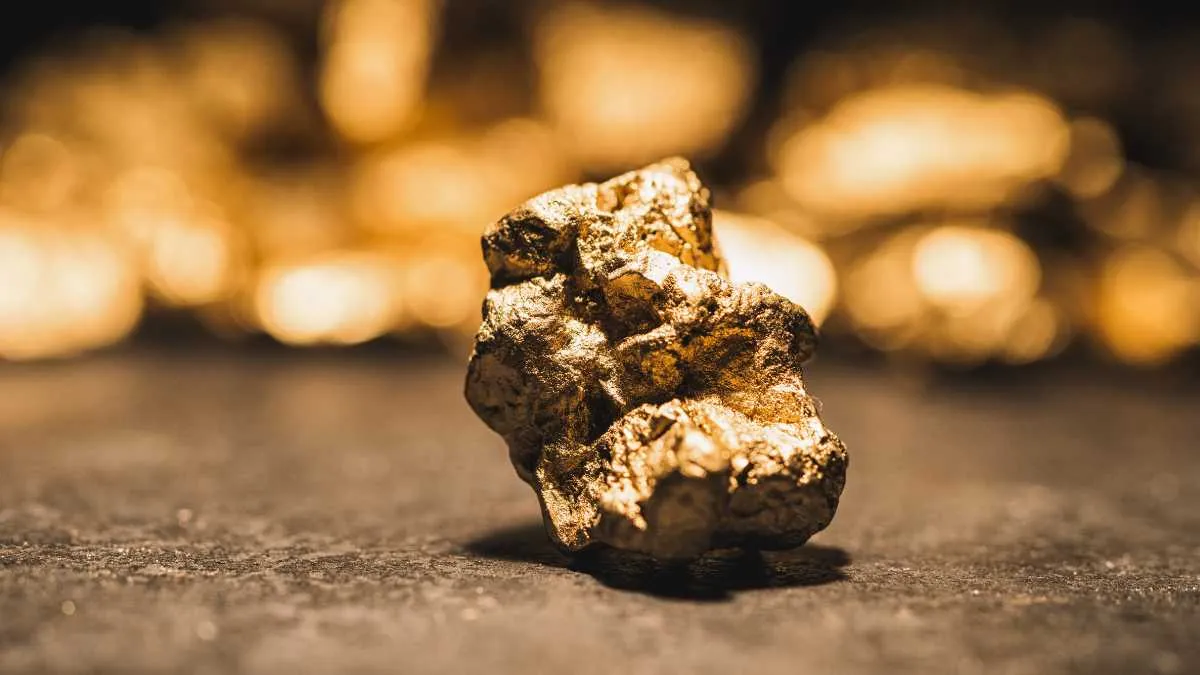 A gold nugget in focus with blurred gold pieces in the background