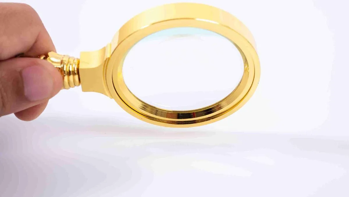 A golden magnifying glass in hand set against a clean white environment