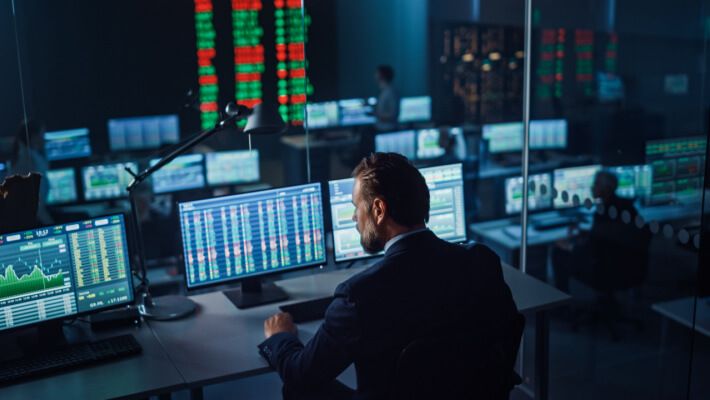 A man analyzing financial data on multiple computer screens