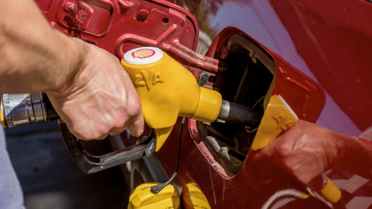 A man hand holding pump filling gasoline on Shell station