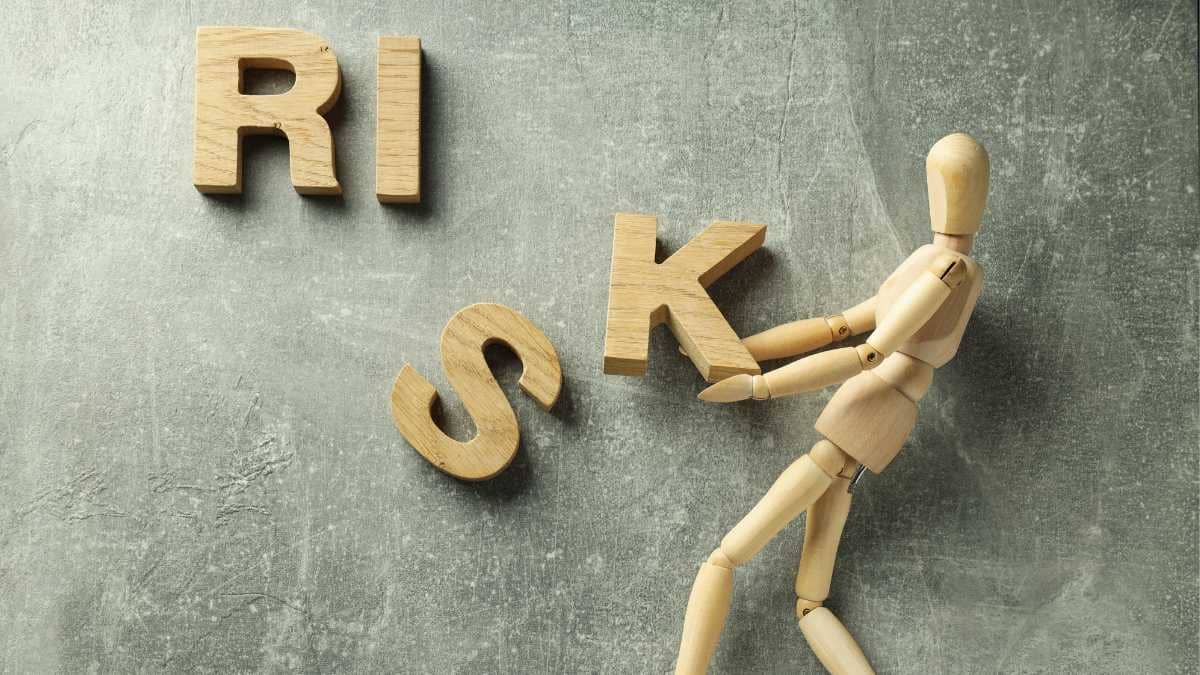 A wooden figure pushing the letters of the word RISK