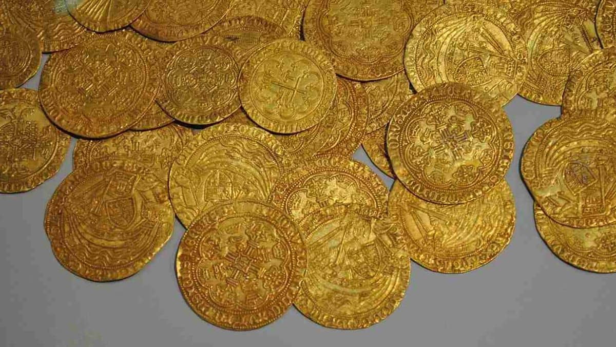 Ancient gold coins scattered on a flat grey surface