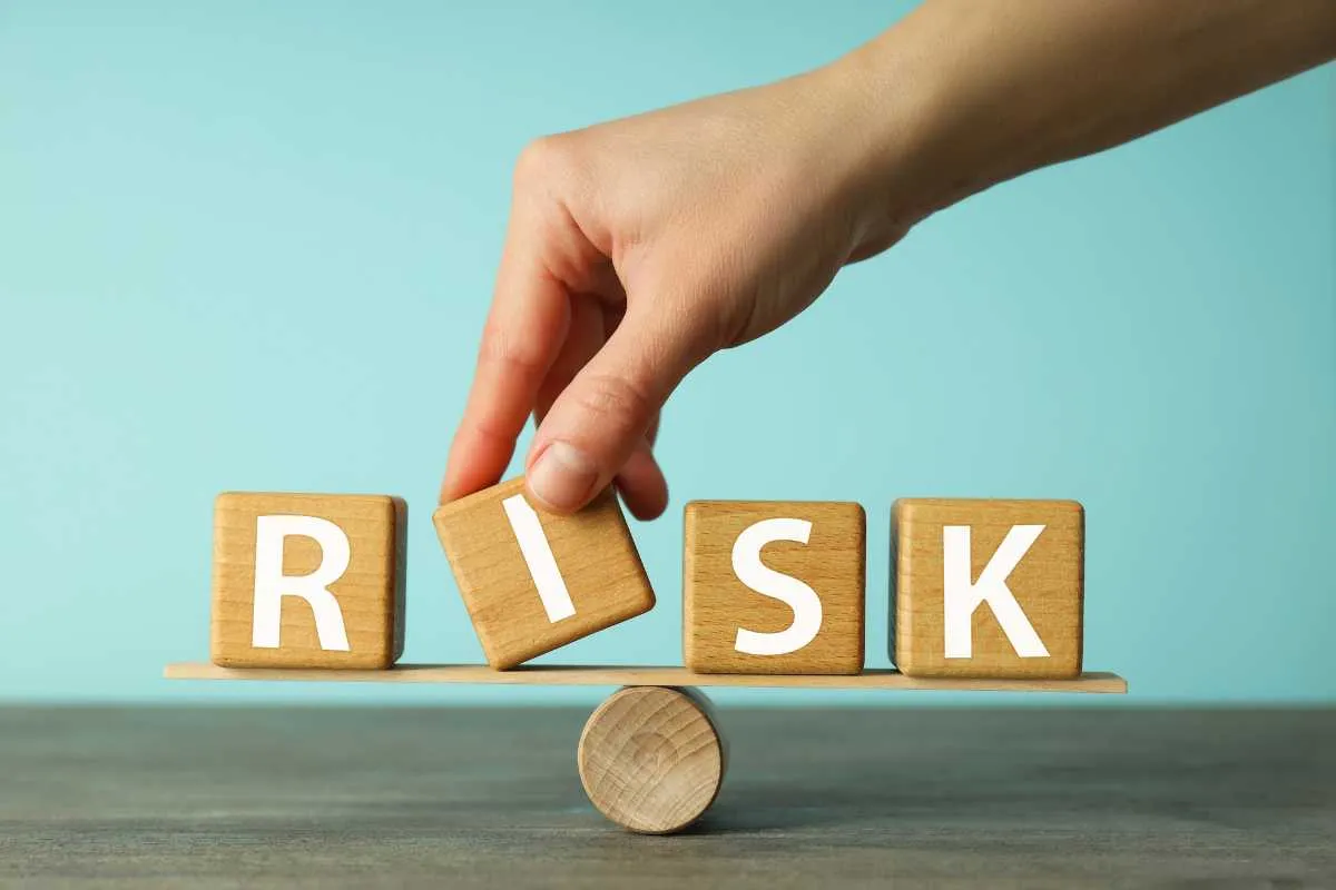 Hand balancing wooden blocks spelling RISK