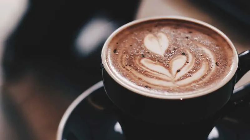 Latte with heart shaped foam art in a black cup