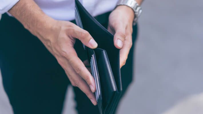 Man standing holding black wallet empty of money