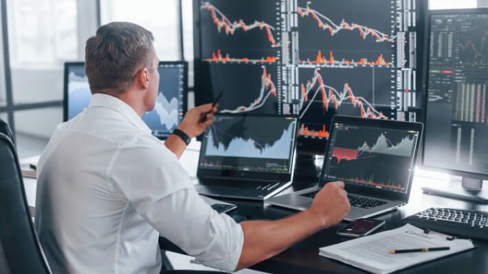 A man holding a pen, focused on a financial chart