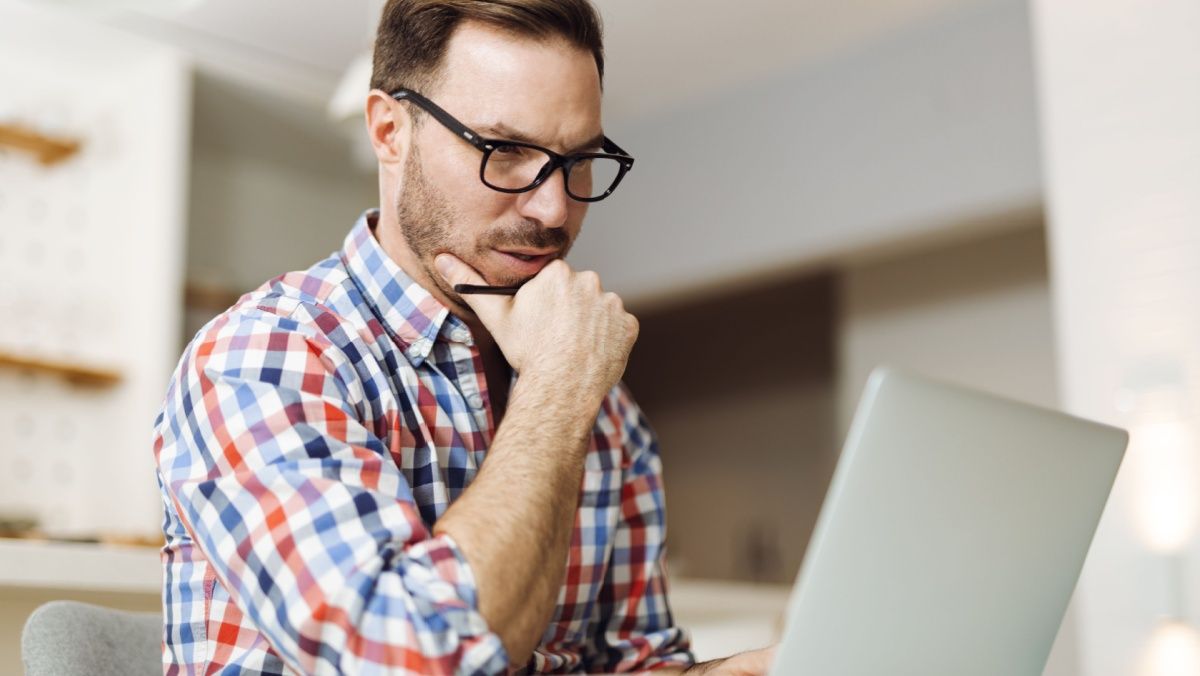 Pensive mid adult man working on a computer at home