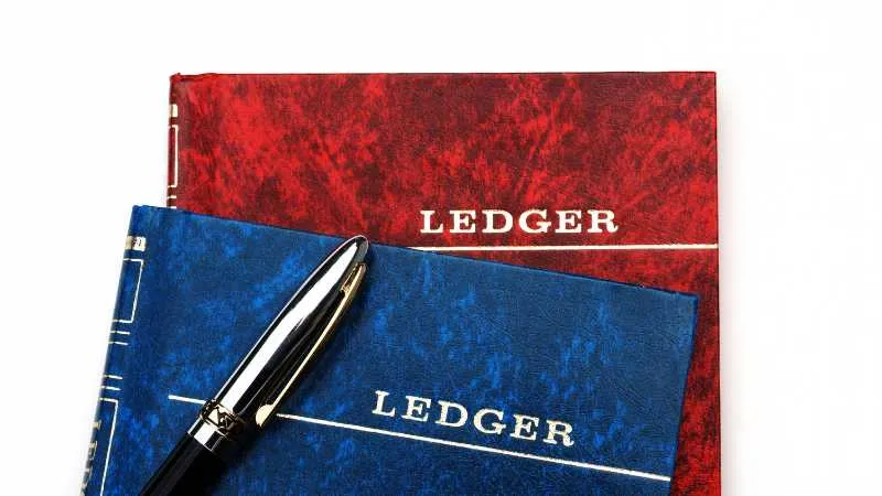 Red and blue ledgers with a pen on white background