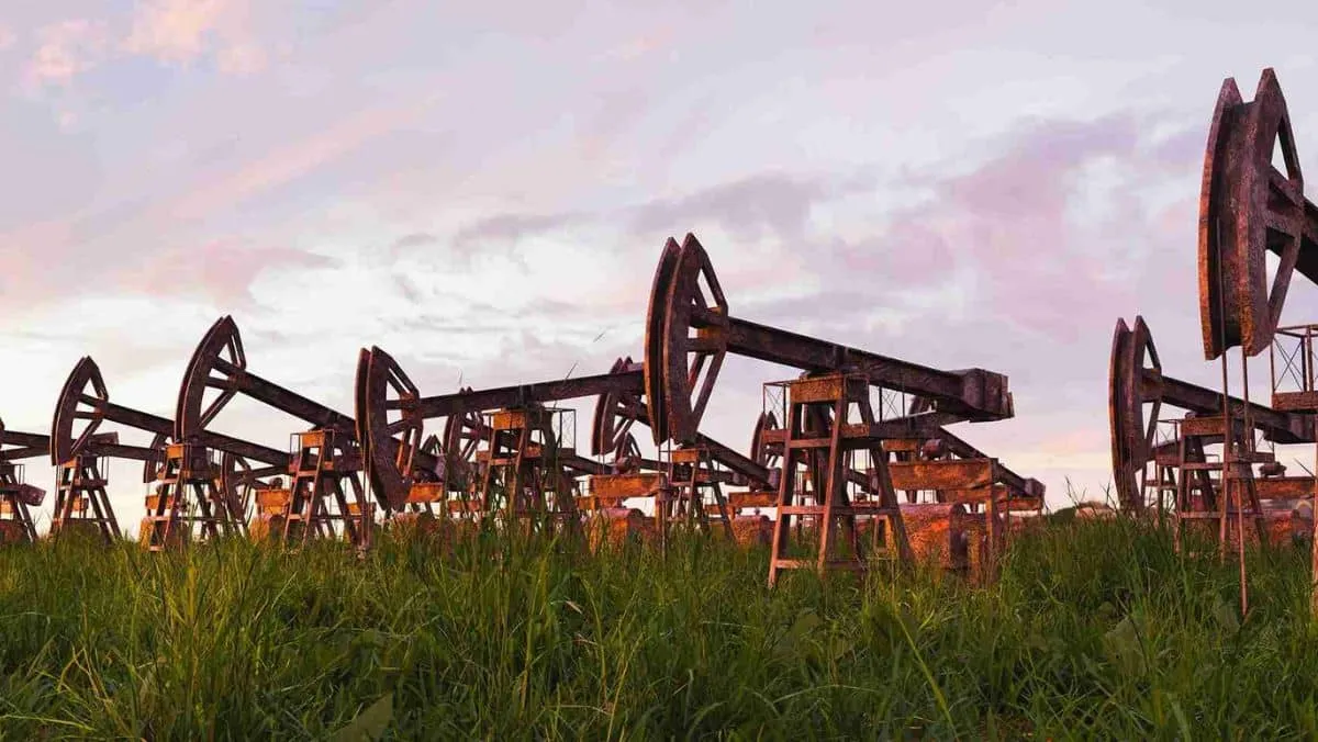 Rust-laden oil extraction equipment dispersed across the grassy meadow