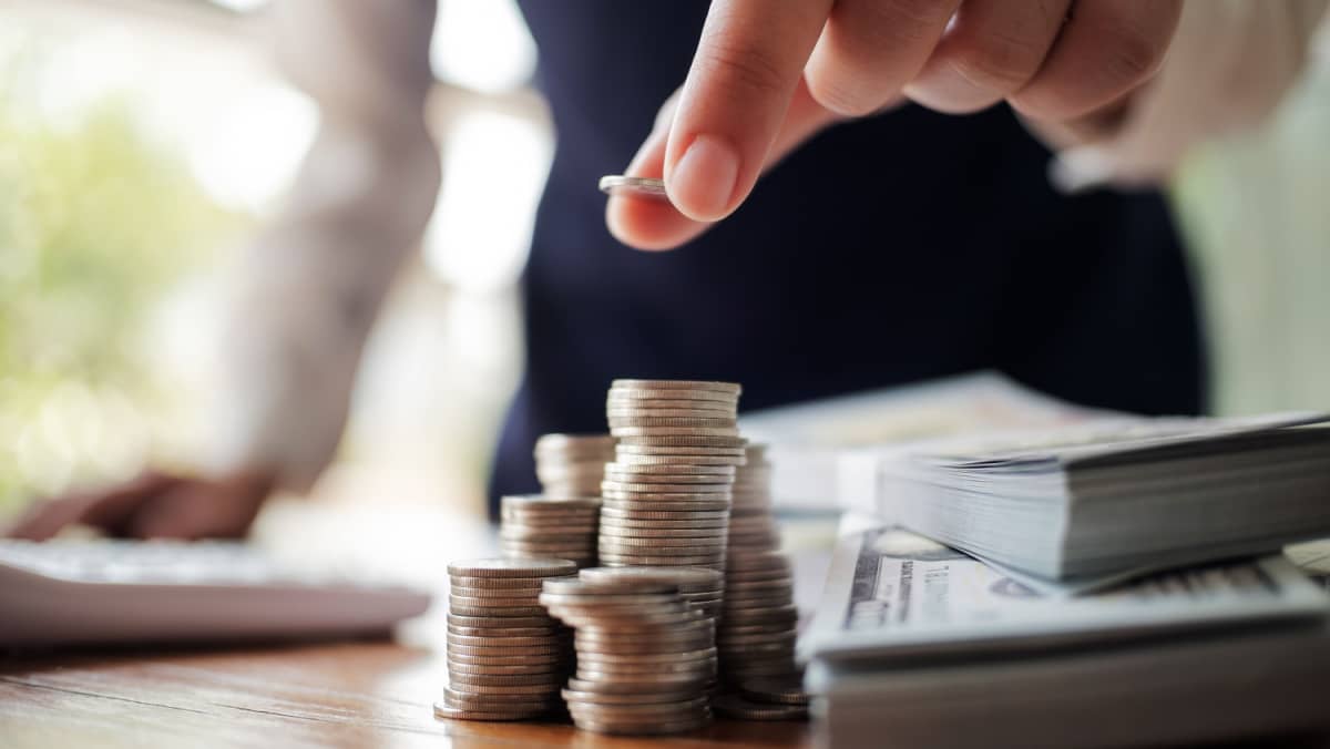 Businessman at work in his office creating a coin stack and managing banknotes