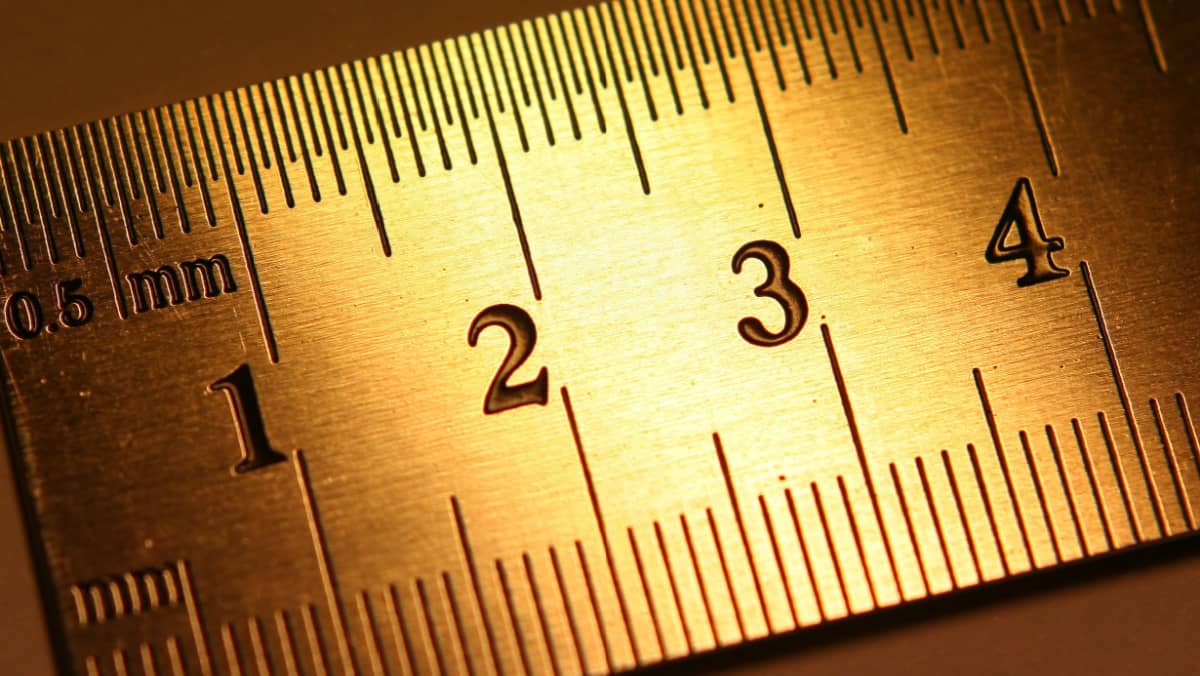 Detailed close up of a golden colored ruler highlighting a measurement of four inches