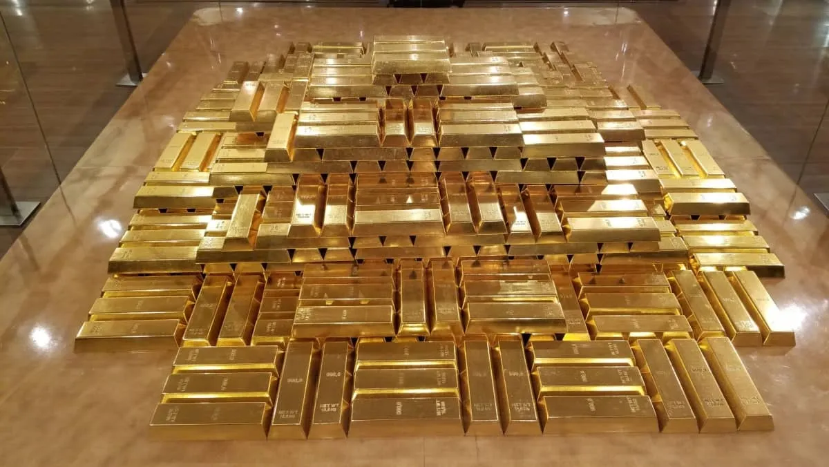 A secure storage area with tons of gold bars enclosed by a glass fence