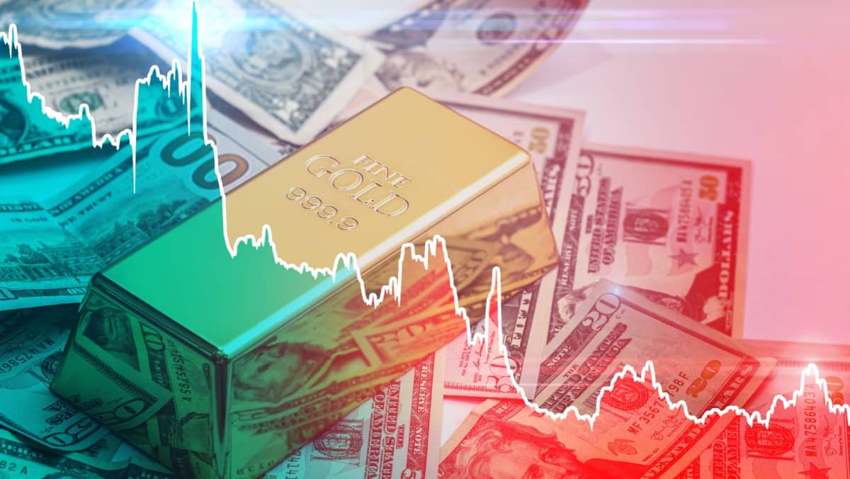 A single gold bar placed above a pile of paper currency with a graph portraying both rising and falling price trends