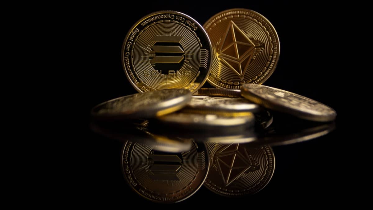 Solana and Ethereum coins gleaming in the dark casting reflections on the surface