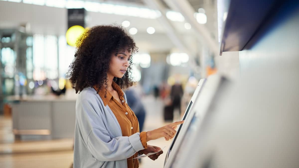 A woman in the airport is making a transaction online through a kiosk