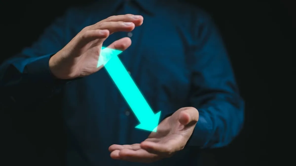 A man in the dark showing his hands with a neon colored arrow pointing in both directions