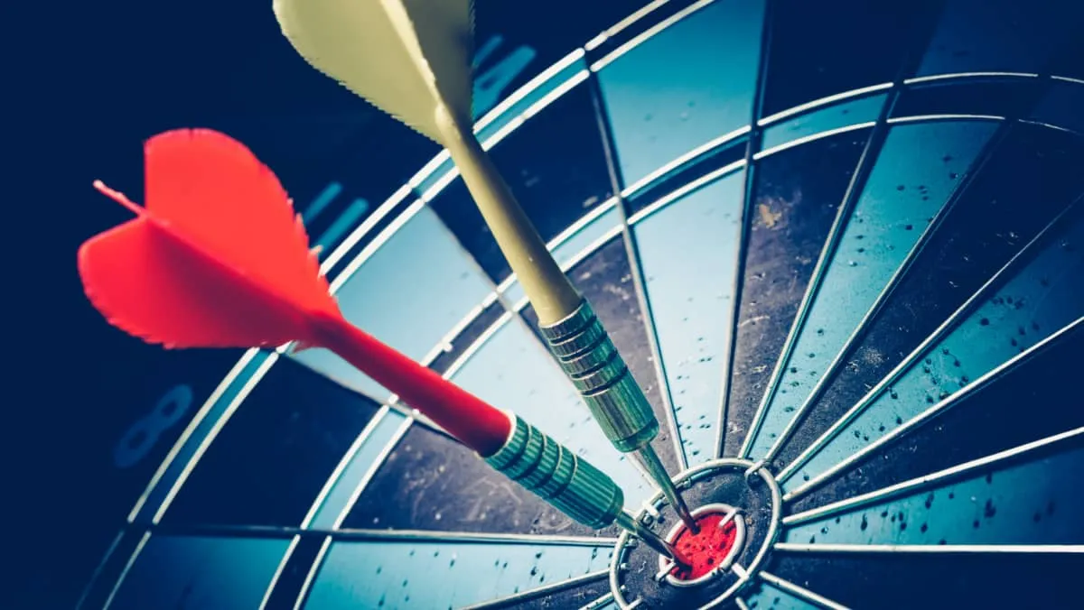 Red and yellow dart arrow in the centre of the target dartboard