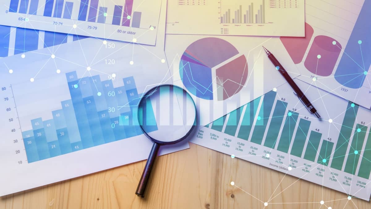 Close up view of a table setting with a magnifying glass over documents showing analytical data