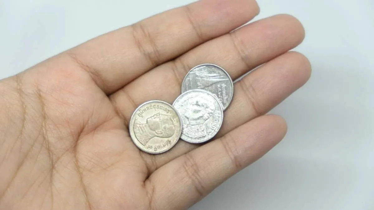 A palm is displayed with three coins made of pure silver