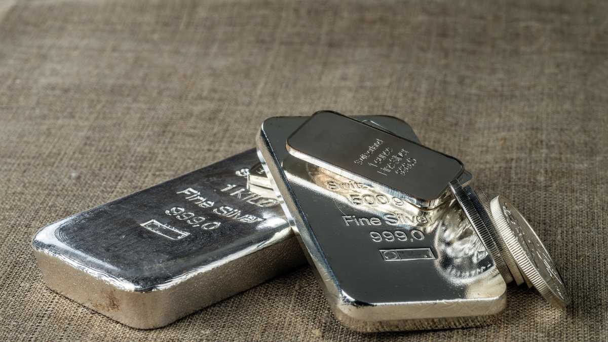 Silver bars and coins on a textured surface