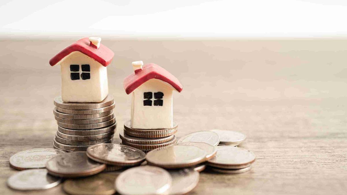 Two miniature houses positioned on a heap of coins